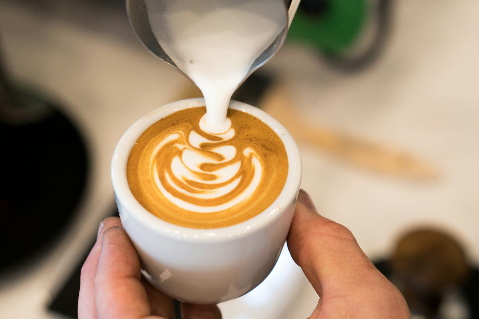 milk being poured on cappuccino