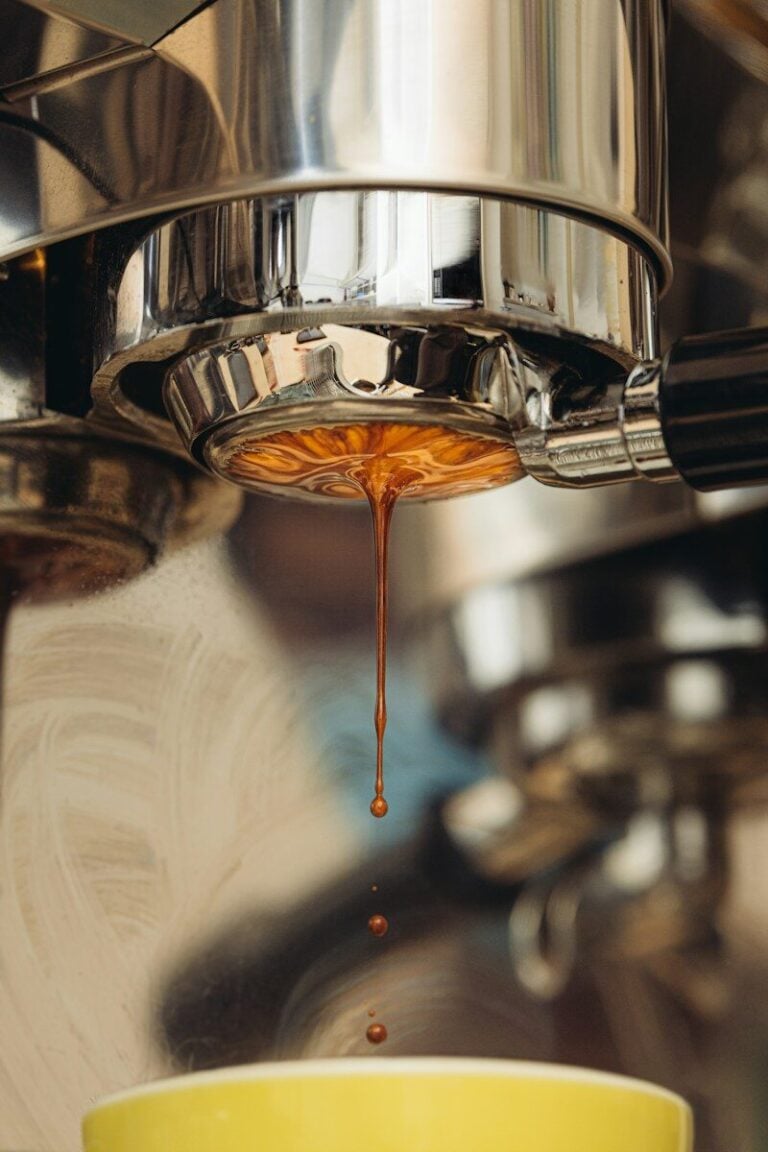 Espresso dripping from a metal portafilter into a yellow cup